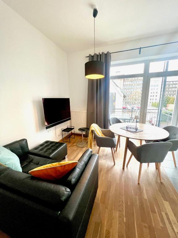 a living room with a black couch and a table at Cooles City-Appartment - Balkon in Bayreuth