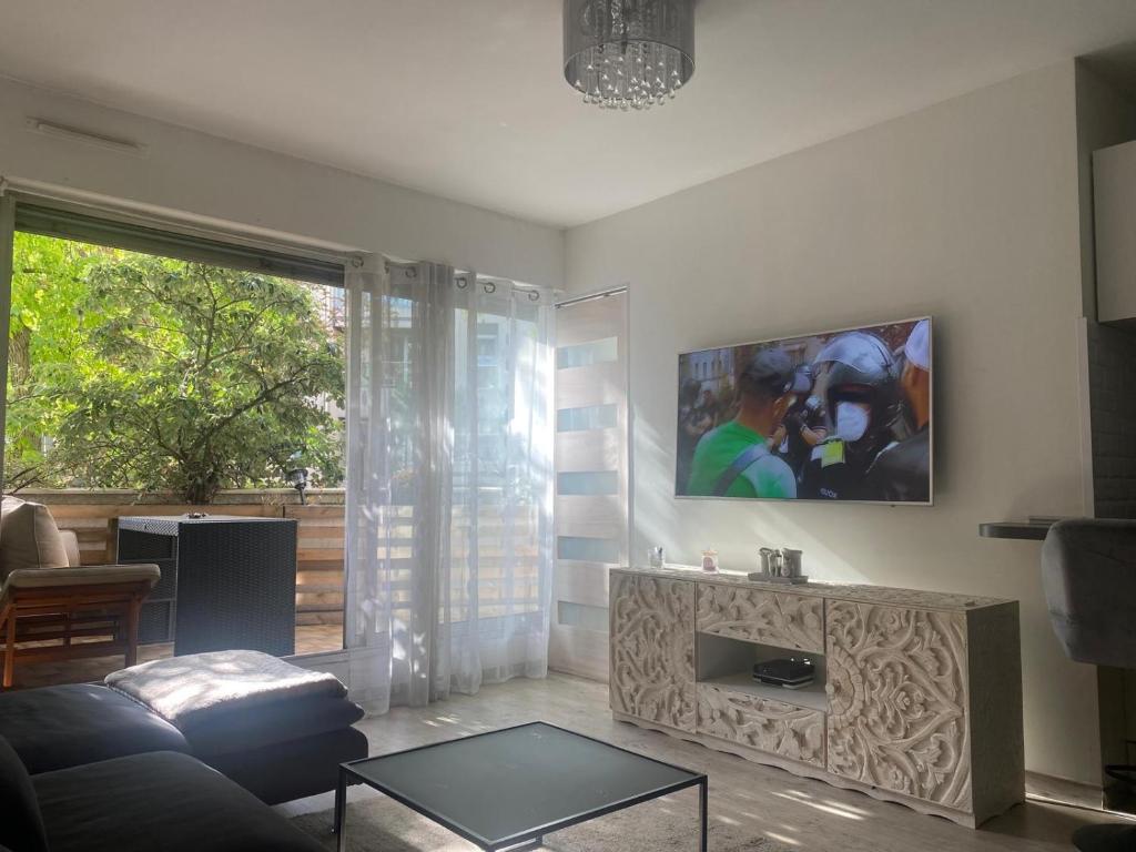un salon avec un canapé et une télévision au mur dans l'établissement Appartement terrasse proche paris, à Saint-Cloud