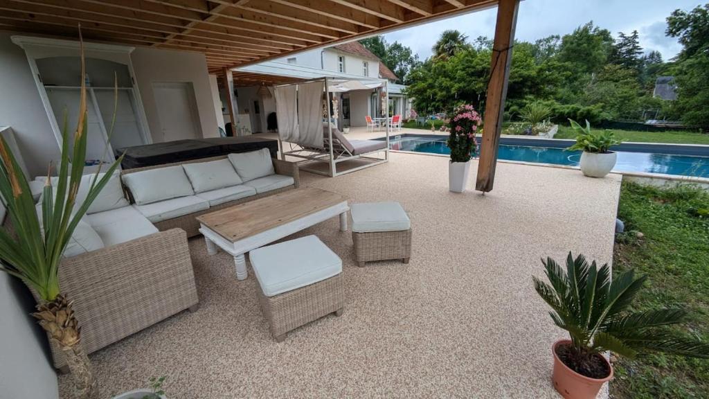 une terrasse avec un canapé, des tables et une piscine dans l'établissement Cosy Arnaya Domaine et Grande Piscine - 1 hectare, à Jurançon