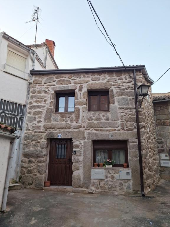 a stone house with a door and two windows at La Escondida in Burgohondo