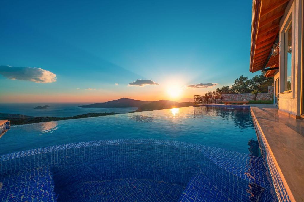 ein Swimmingpool mit einem Sonnenuntergang im Hintergrund in der Unterkunft Akasya Villas in Kalkan