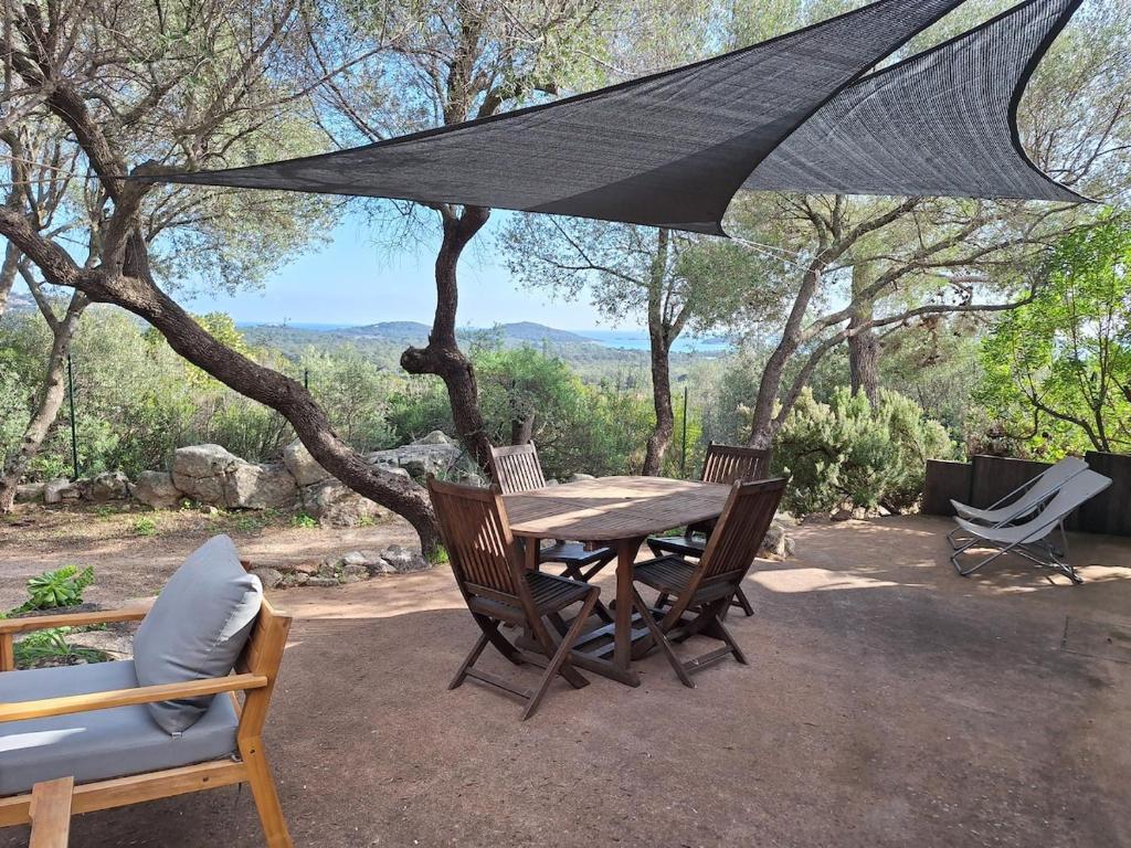 une table et des chaises en bois sous un parasol noir dans l'établissement I Caselli, mini villa Vue Mer dans résidence calme et arborée, à Lecci