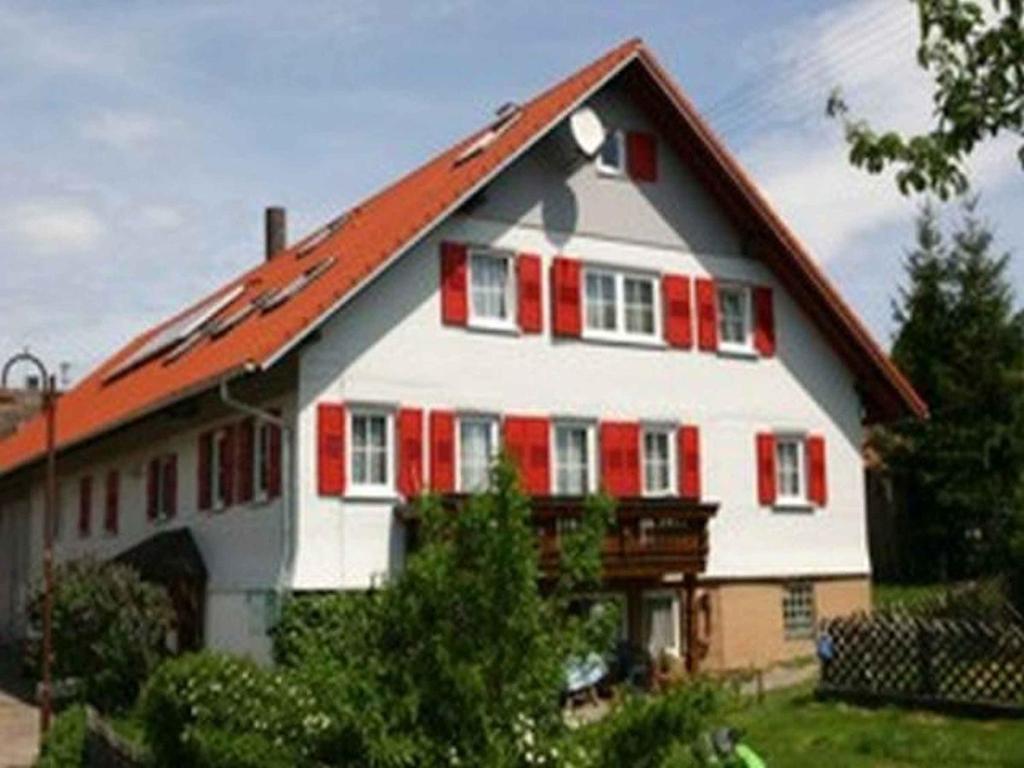 a white and red house with red shutters at Ferienhof Hirschfeld in Pfalzgrafenweiler