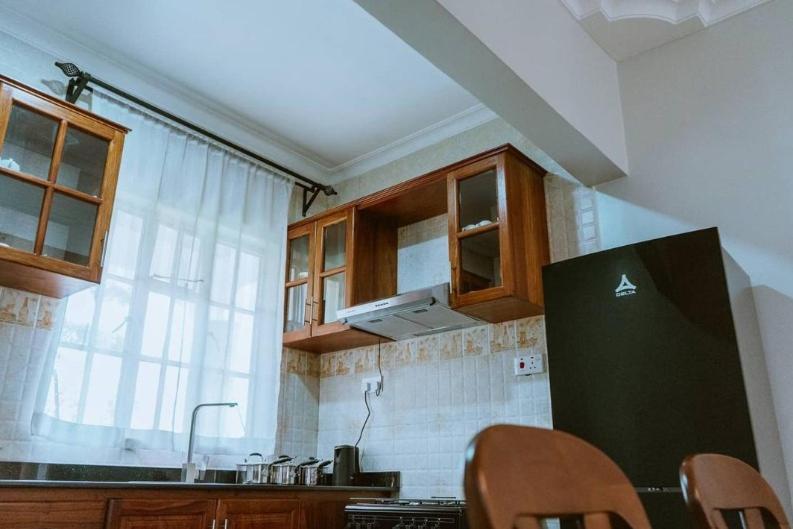 a kitchen with wooden cabinets and a black refrigerator at Iwandaa Lodge And Apartments in Sokon