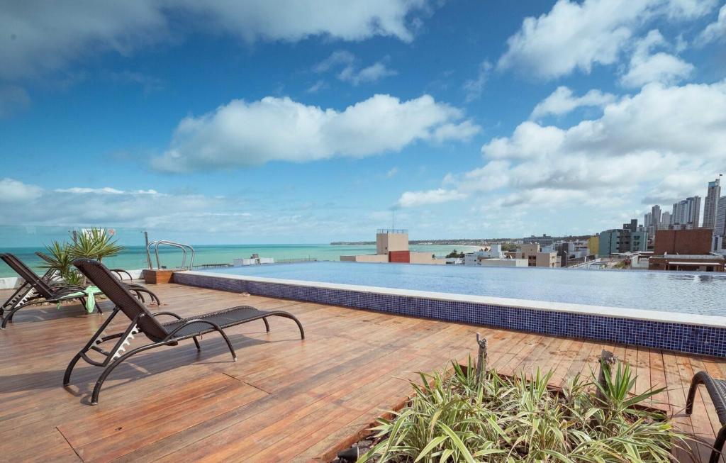a swimming pool with two chairs on a deck at Apto c otima localizacao a 120m da praia de Tambau in Tambaú