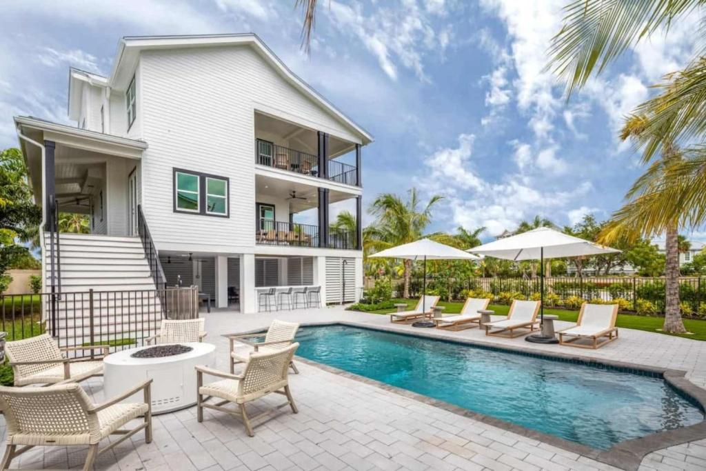 a house with a swimming pool with chairs and umbrellas at New The Windrose House - Pool & Pets in Key West