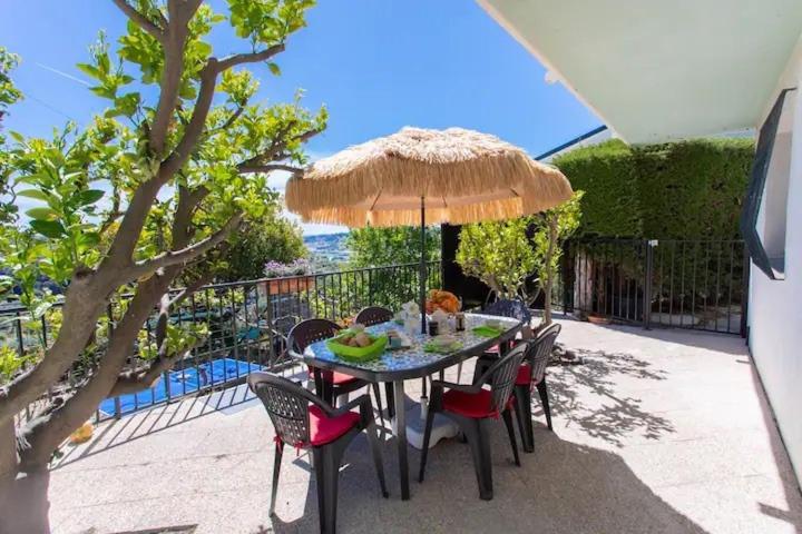 une table avec des chaises et un parasol sur une terrasse dans l'établissement l'échappée belle - vineyard-jacuzzi and BBQ, à Nice