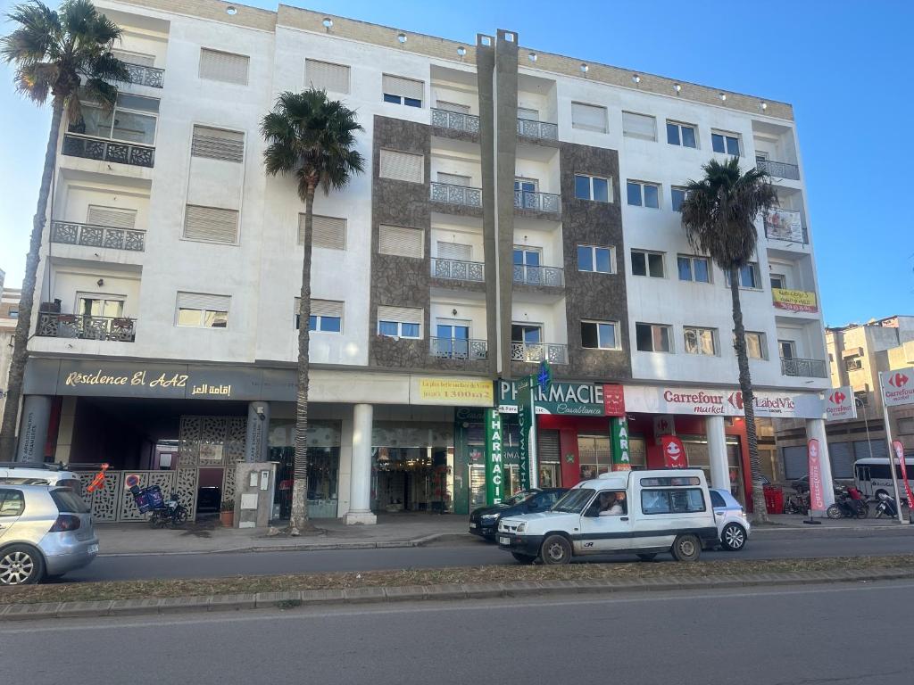 two cars parked in front of a building with palm trees at La Remaz 35 in El Jadida
