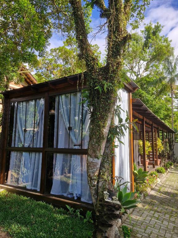 a small house with a tree in front of it at Pousada Encantos do Estaleiro in Balneário Camboriú