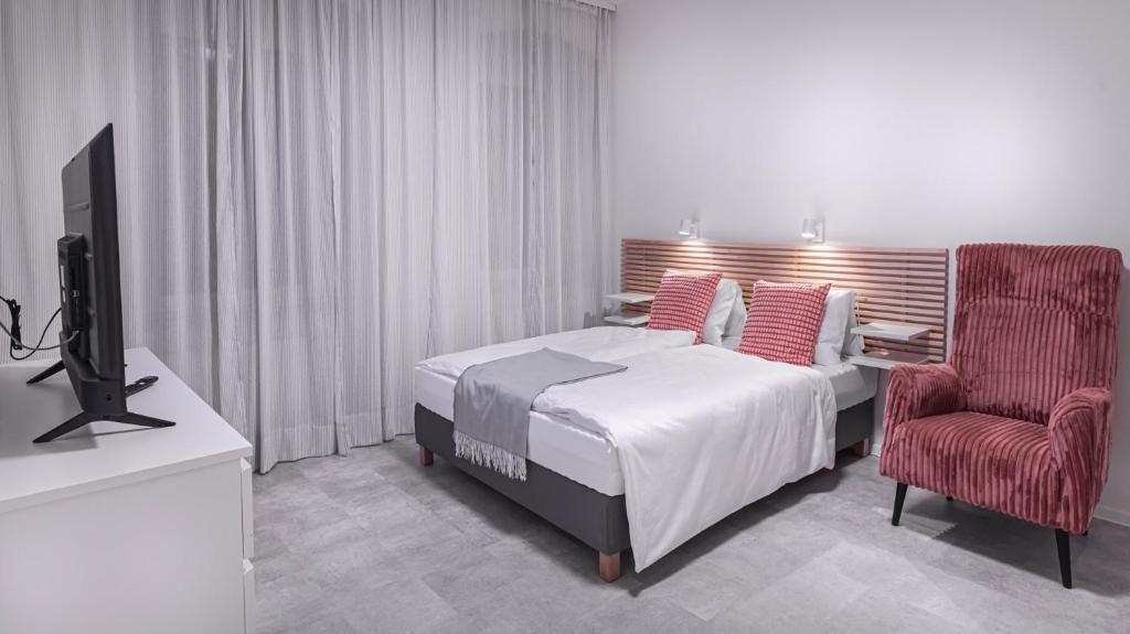 Un dormitorio con una cama, un televisor y una silla. en Apartments - Restart House Poprad, en Poprad