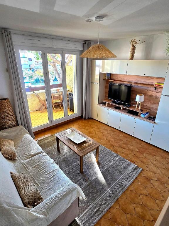 un salon avec un canapé et une télévision dans l'établissement Fidji - à 7min de la mer à pied, avec balcon et parking - BY Auraconciergerie, aux Lecques