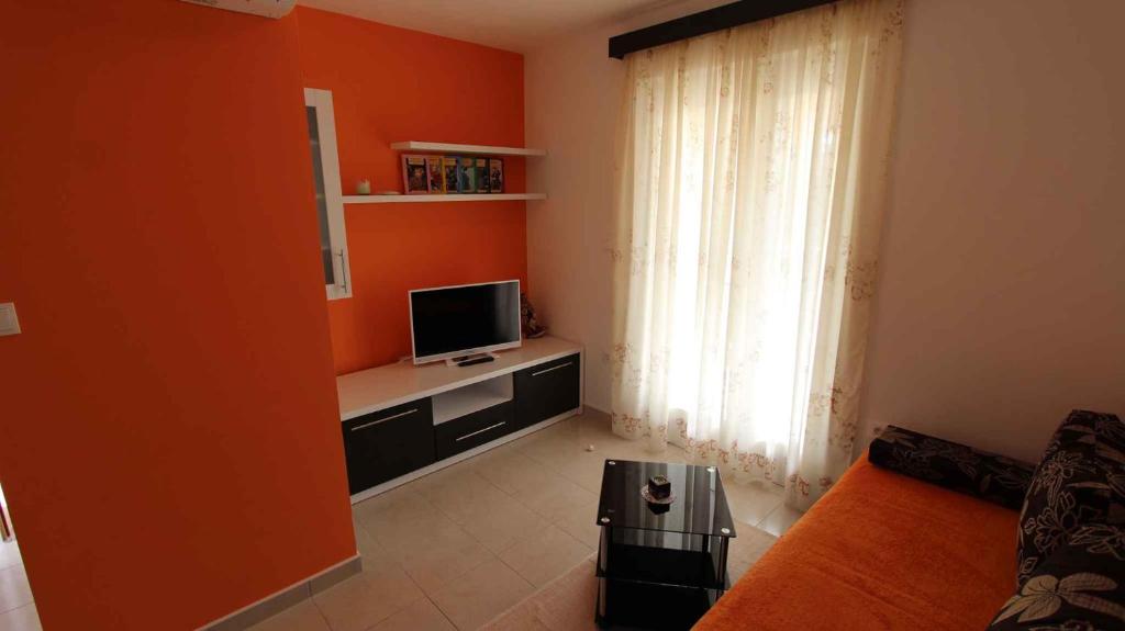 salon z pomarańczową ścianą i telewizorem w obiekcie Malinska Apartment 2 w mieście Sveti Anton