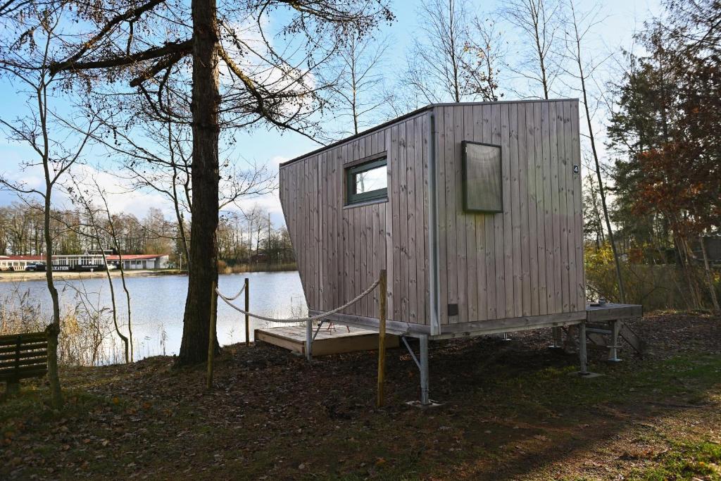 une petite maison sur un quai à côté d'un lac dans l'établissement Sleep Space 4 - Green Tiny Spot Friesland, à Schortens