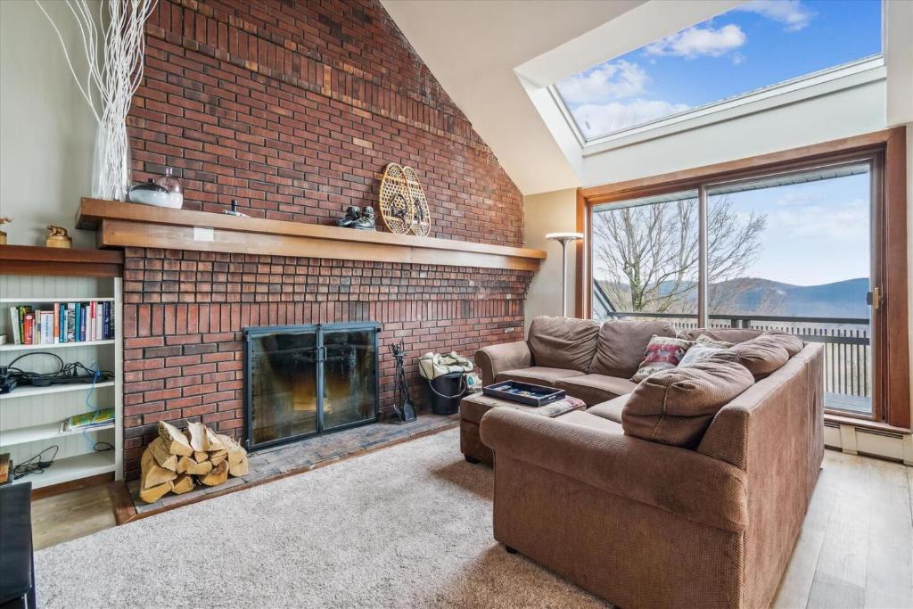 a living room with a brick fireplace and a couch at Sunrise Timberline K8 in Killington