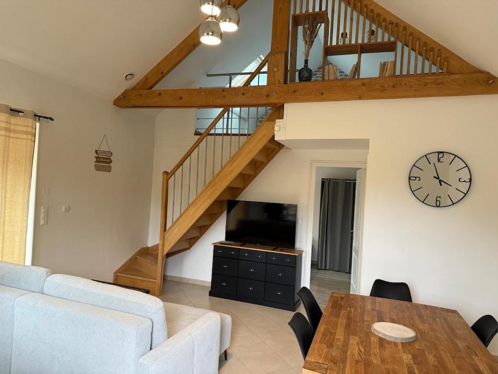 a living room with a table and a clock at Maison cosy du Bocage Ornais in Condé-sur-Sarthe