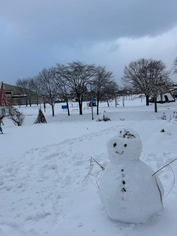 a snowman sitting in the snow in a field at Kame in Niseko