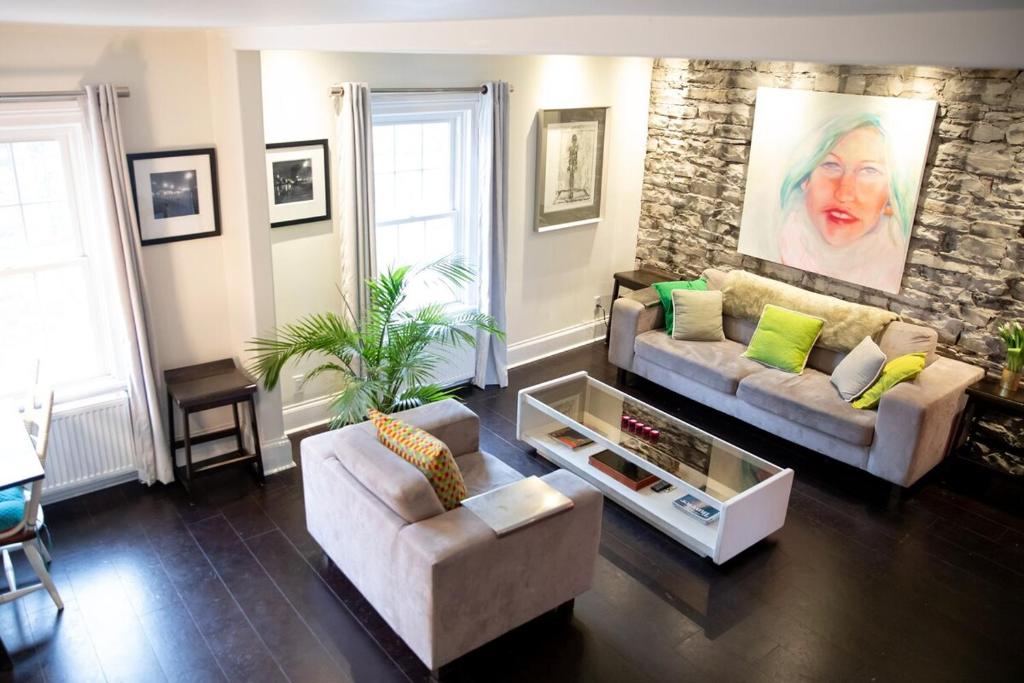 een woonkamer met een bank en twee stoelen bij KingstonStays Spacious Historic Downtown Stableman's House Loft in Kingston