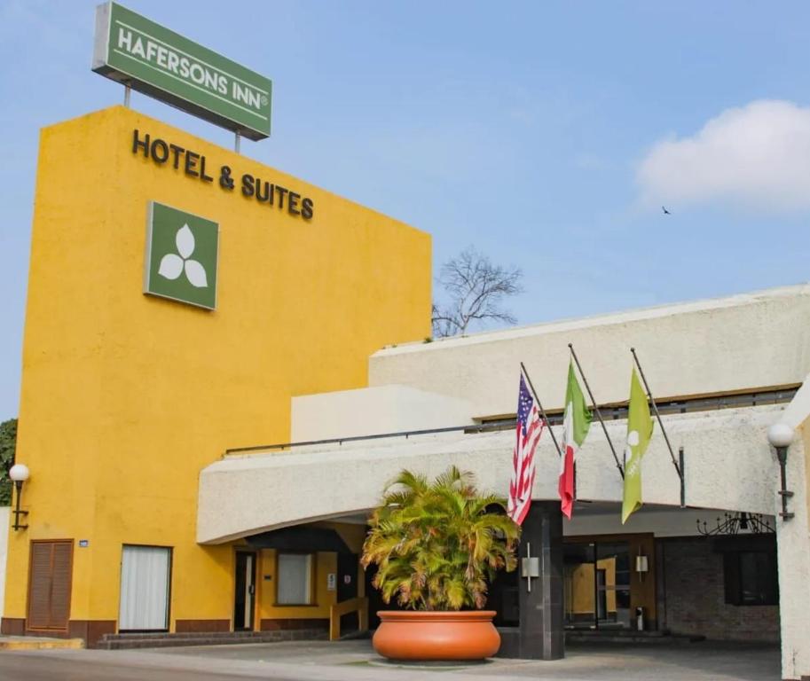 a hotel and suites building with flags in front of it at Hafersons Inn Hotel Suites in Madero