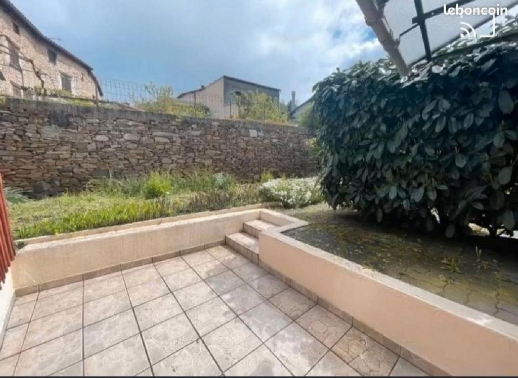 a garden with a stone wall and a patio at Maison Cantalou in Massiac