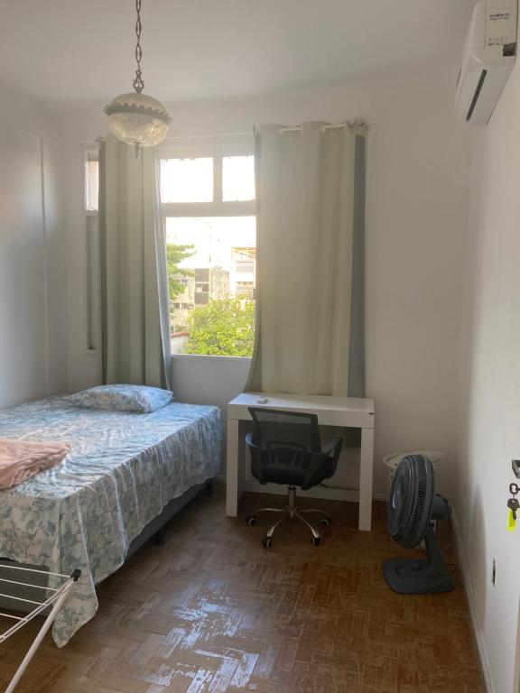een slaapkamer met een bed, een bureau en een raam bij Apartamento na Pituba in Salvador