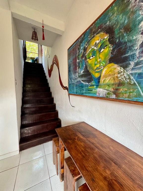 a painting of a woman on a wall next to a staircase at Casa Boa Vida GuestHouse in Itacaré