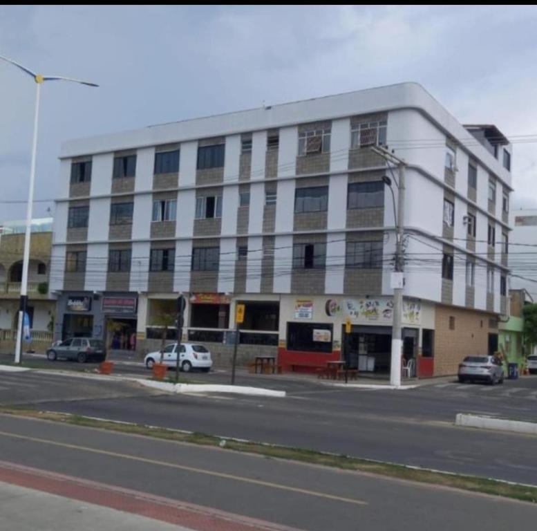 Un gran edificio blanco al costado de una calle. en Edifício Patinhas, en Marataízes