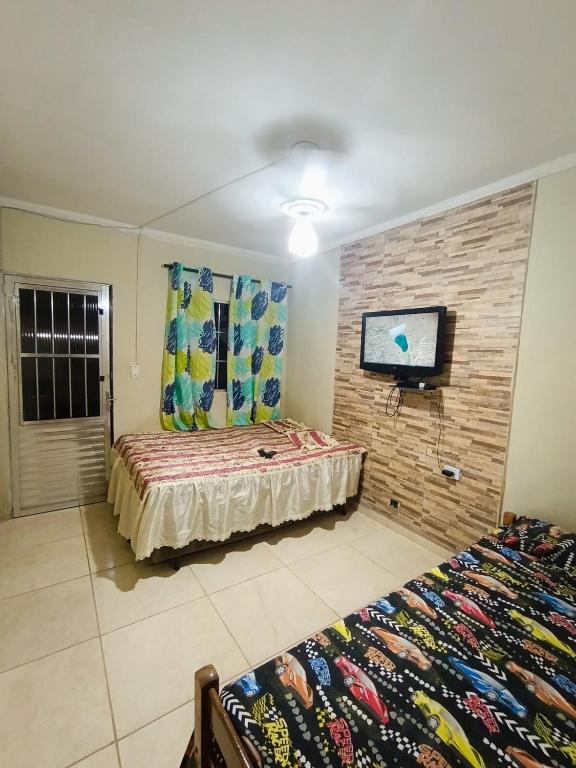 a bedroom with two beds and a flat screen tv at kitnet family - 2 quadras da praia da Enseada in Guarujá
