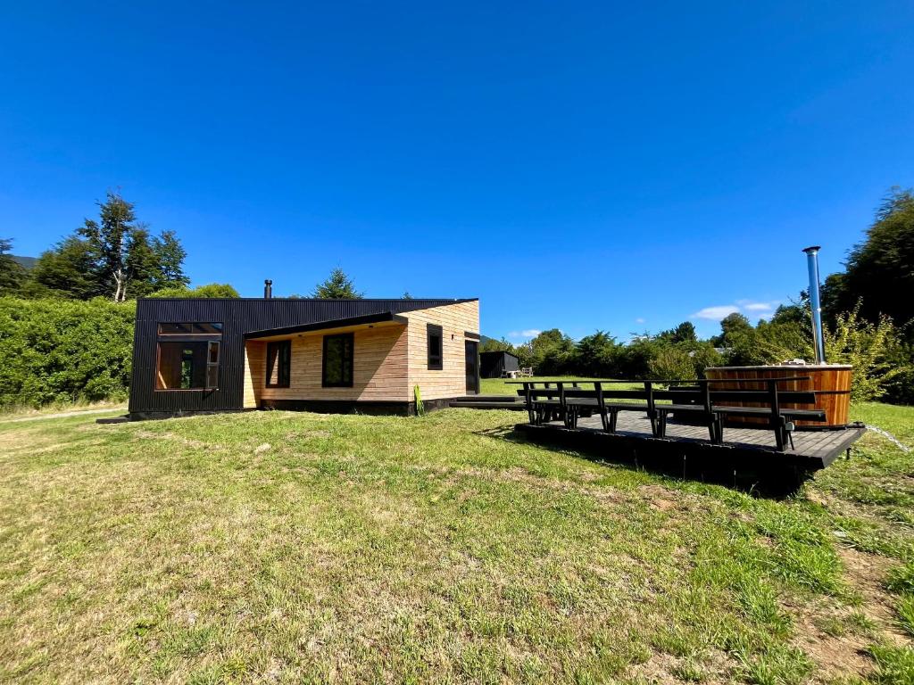 a small house on a grassy field next to a building at Huelemolle Lodge Pucón in Pucón