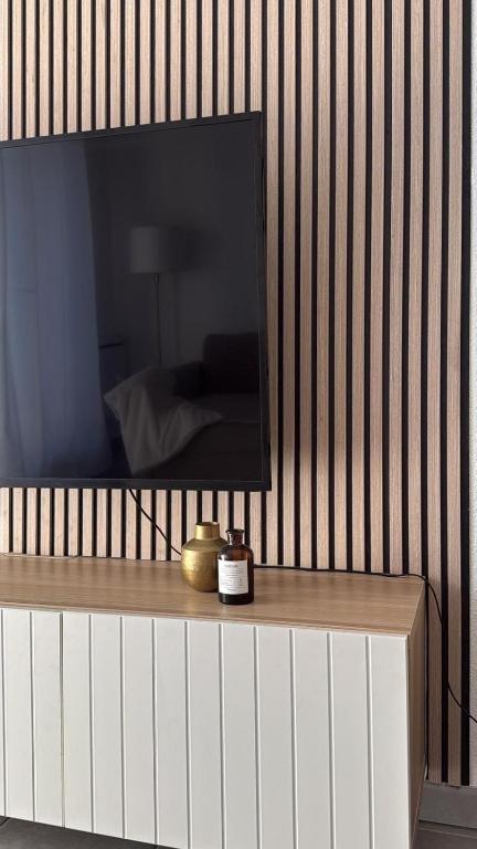 une télévision sur un mur avec une table et une horloge dans l'établissement Residence Villa rose T3 parking privé, à Toulouse