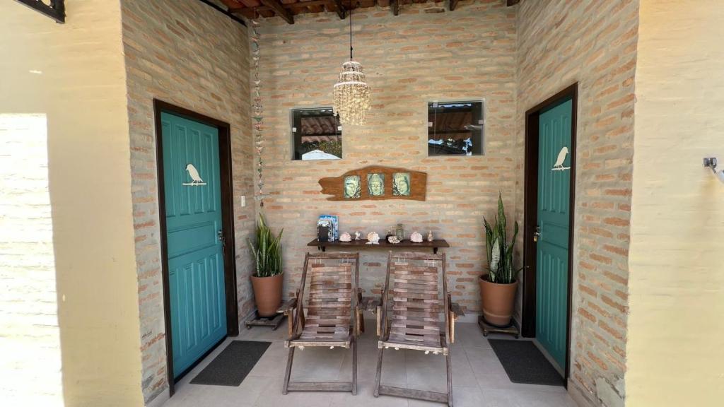 a patio with chairs and a table with green doors at Suítes Curió - Passarim Hospedagem in Cumuruxatiba