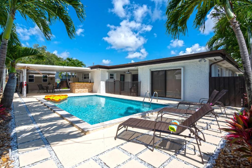 a swimming pool with two chairs and a house at Tropical house Miami in Cutler Bay