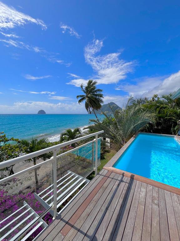 a wooden deck with a swimming pool next to the beach at Leynita Bay in Le Diamant