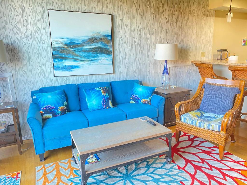 Una sala de estar con un sofá azul y dos sillas. en OCEANVIEW 2 Bedroom - WALK TO DOWNTOWN, en Kailua-Kona