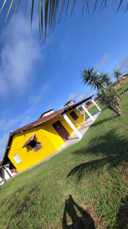 une maison jaune avec un palmier devant dans l'établissement Recanto Bougainville, à Angelim