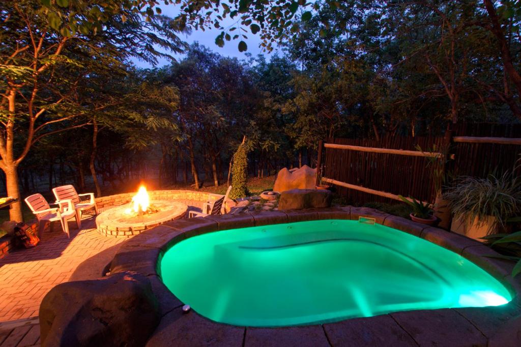 a swimming pool in a backyard with a fire pit at Tranquil Nest in Hazyview