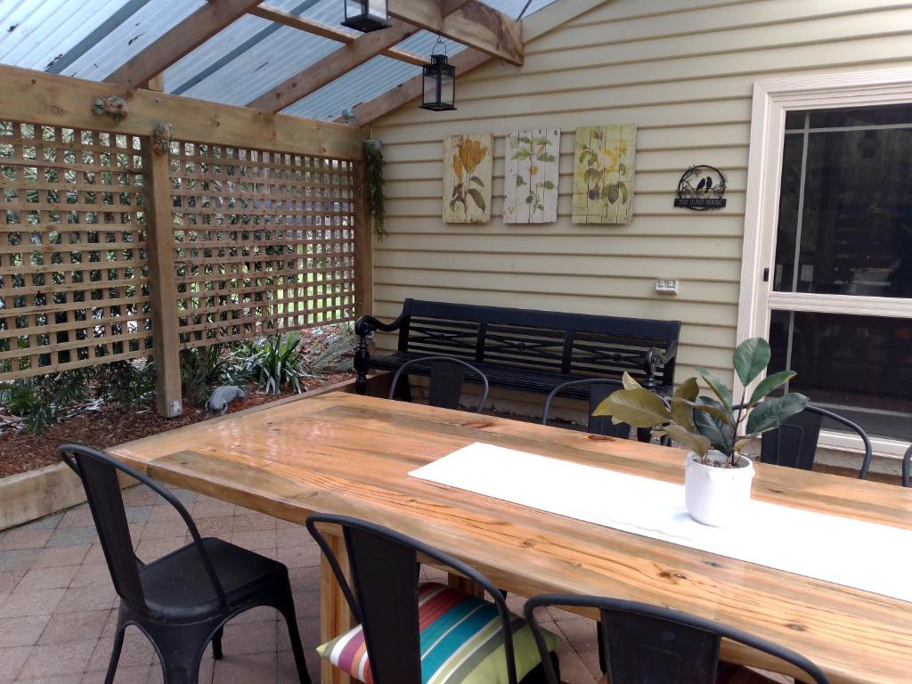 a wooden table and chairs on a patio with a bench at The Olive House Tasmania in Flowerdale