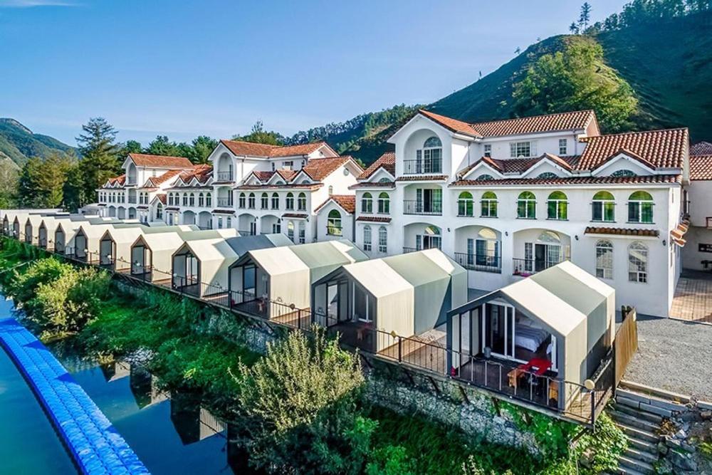 un grand bâtiment blanc à côté d'une étendue d'eau dans l'établissement Hongcheon Monterio Resort, à Hongcheon