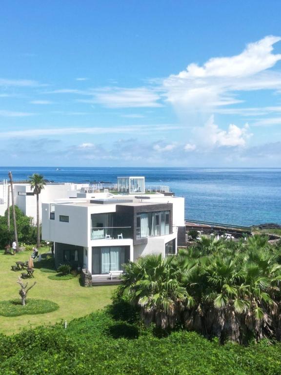 a large white house with the ocean in the background at Hello Gimnyeong in Jeju