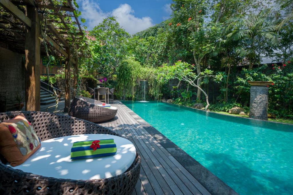 a swimming pool with a table and chairs next to it at Villa Kapungkur in Jimbaran