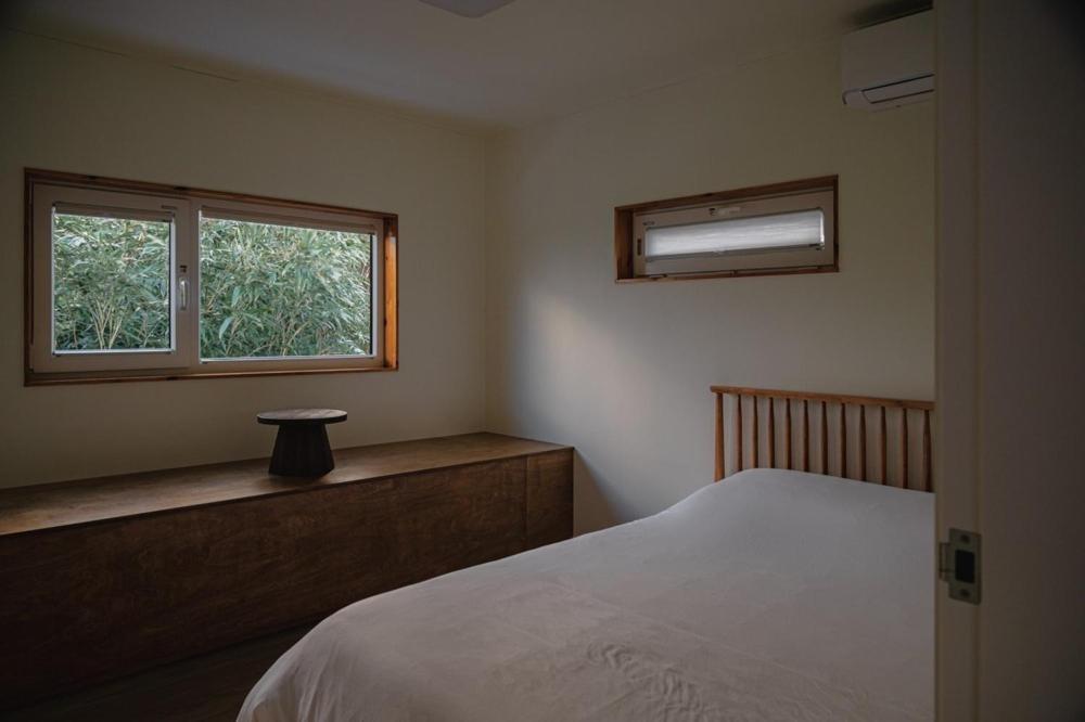 a bedroom with a bed and a window at Jeju Sin-eom-an-gil A in Jeju