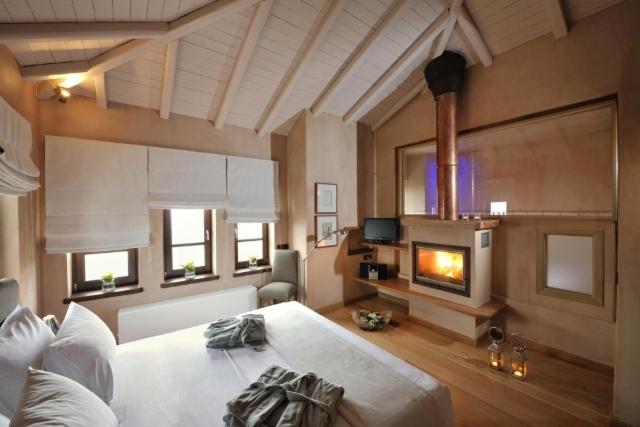 duży pokój z łóżkiem i kominkiem w obiekcie Valeni Boutique Hotel & Spa w mieście Portariá