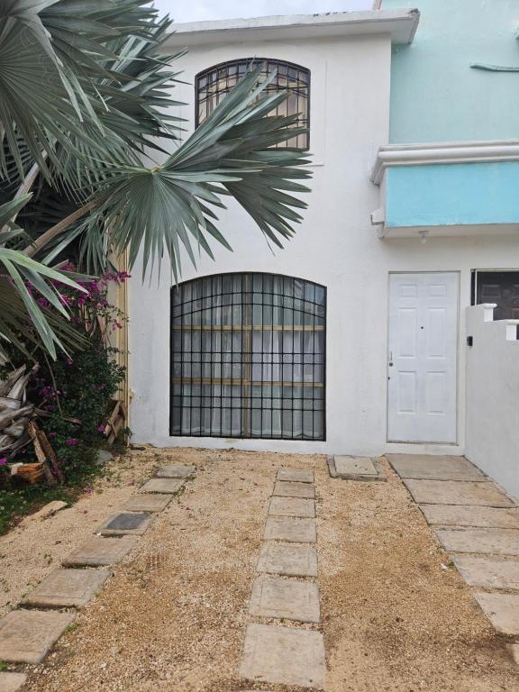 una casa blanca con una puerta y una palmera en Porto Vientos, en Cancún