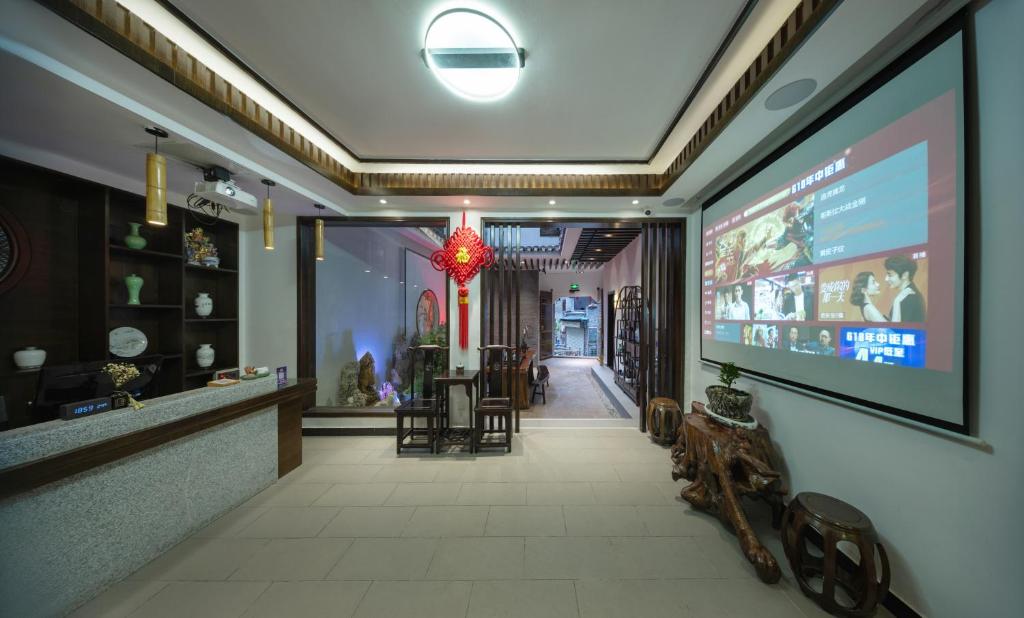 凤凰FenghuangQixin Guesthouse的墙上有大屏幕的餐厅