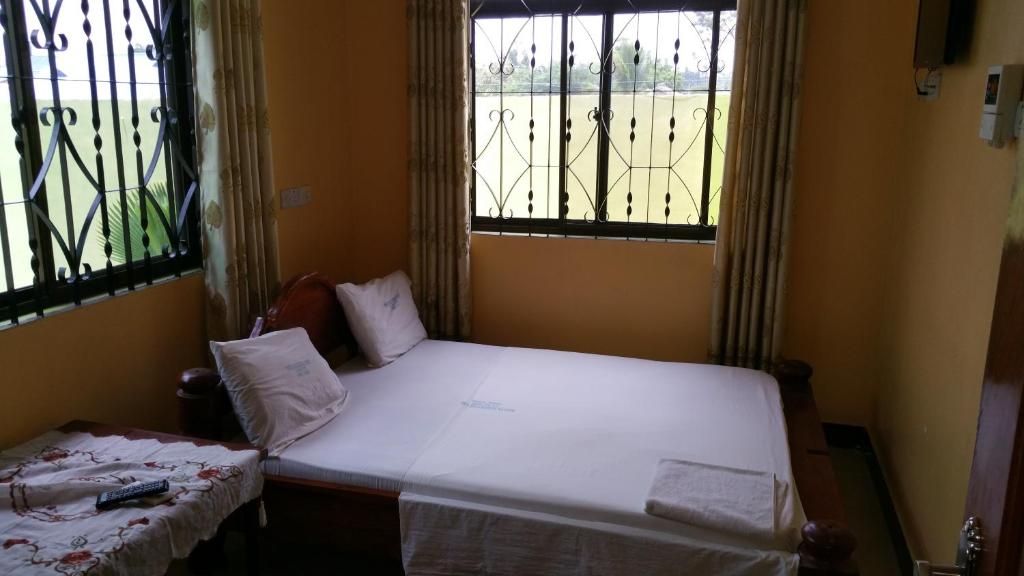 niewielka sypialnia z łóżkiem i 2 oknami w obiekcie Mauya Executive Lodge w mieście Dar es Salaam
