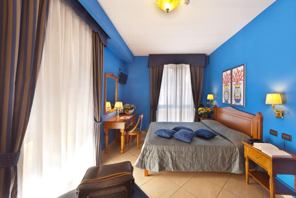 Schlafzimmer mit blauen Wänden und einem Bett mit blauen Kissen in der Unterkunft Ulisse Deluxe Hostel in Sorrent