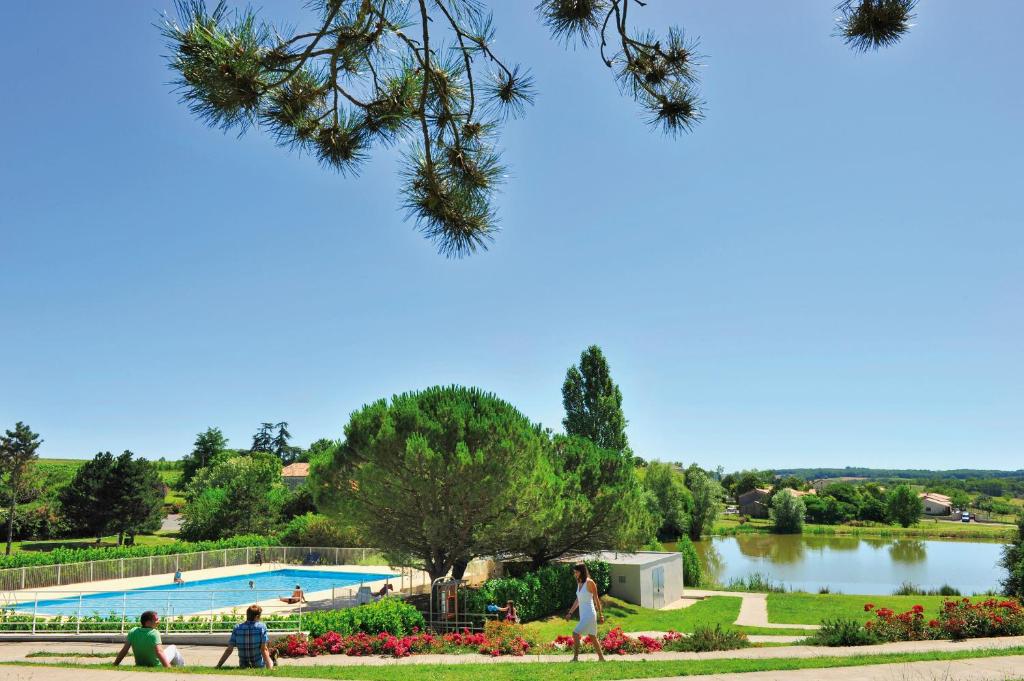 a swimming pool in a park next to a lake at VTF Le Domaine du Peyrichoux in Singleyrac