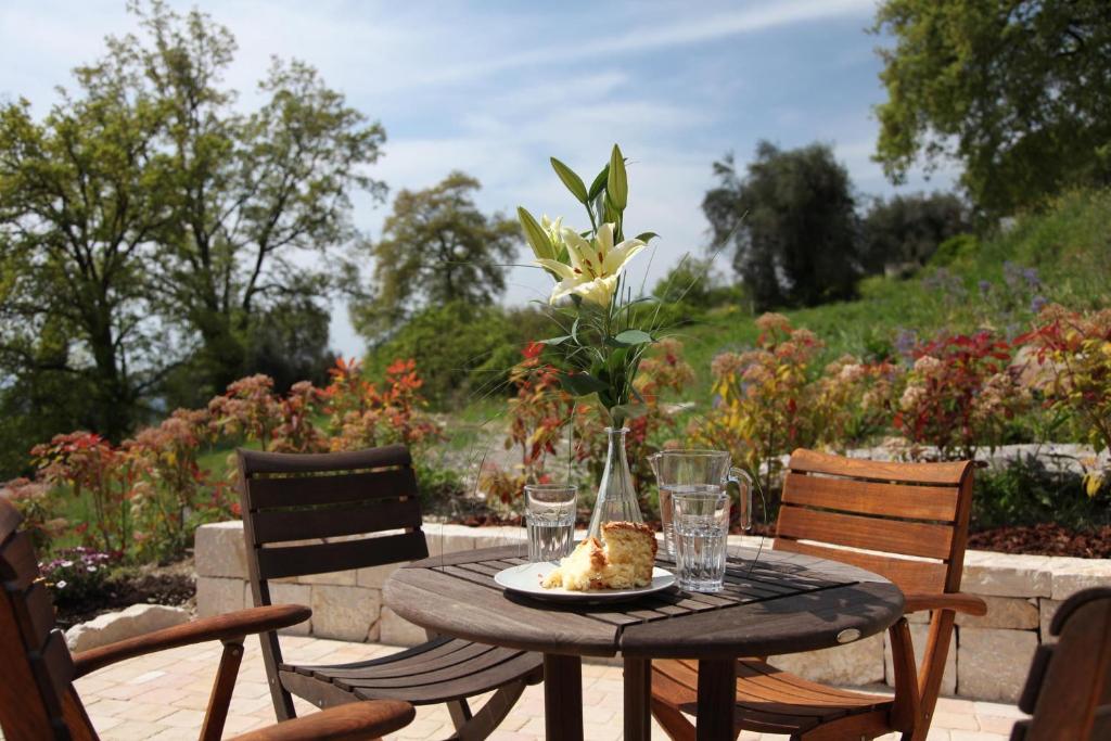 une table avec une assiette de nourriture et un vase avec une fleur dans l'établissement Olives et Libellules, à Vence
