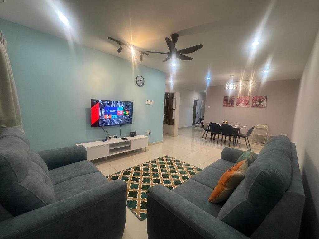 Una sala de estar con dos sofás azules y un televisor. en Cozy homestay Manhattan Ipoh,12 pax 怡保民宿, en Ipoh