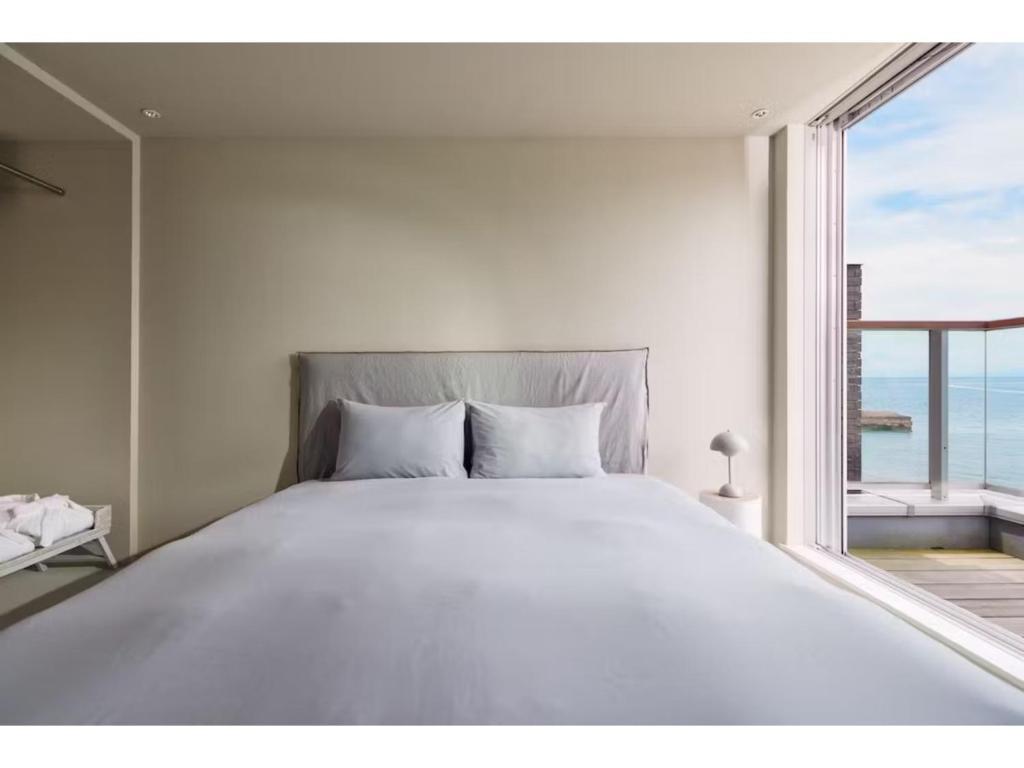 a white bedroom with a large bed and a window at &SUN mini mini - Vacation STAY 17824 in Yokosuka