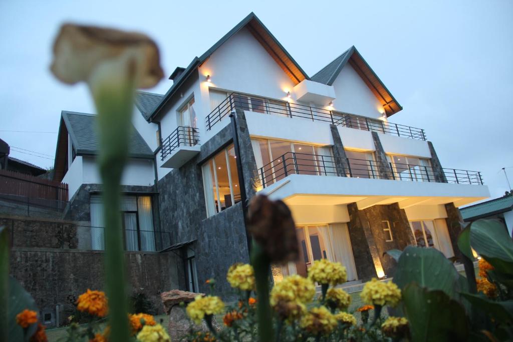 a house with a balcony and flowers in the foreground at Serenus Boutique Villa in Nuwara Eliya